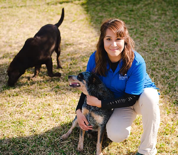 Staff member hugging dog with dog in background at The Pet Resort on Main near Corpus Christi, TX